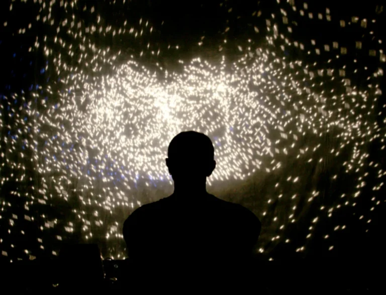 Silhouette eines Performers vor funkelndem Lichtmuster auf Leinwand – Schattentheater-Performance „17 Sätze über das Licht"