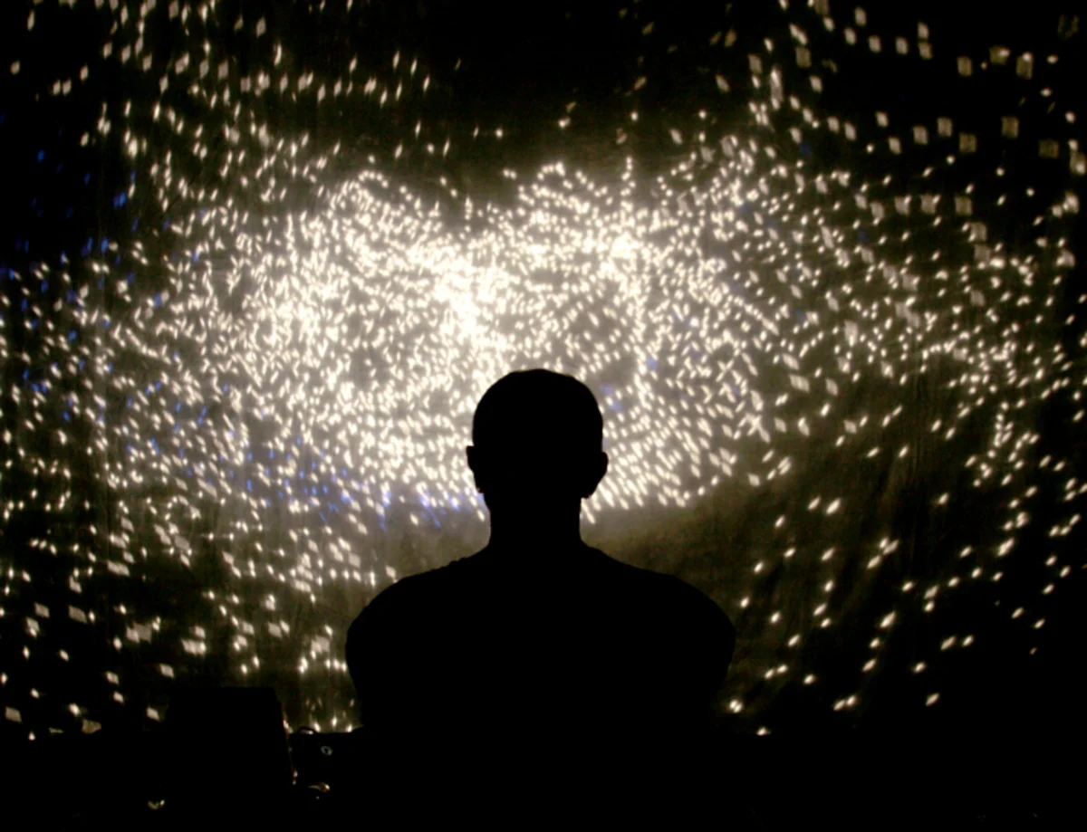Silhouette eines Performers vor funkelndem Lichtmuster auf Leinwand – Schattentheater-Performance „17 Sätze über das Licht"