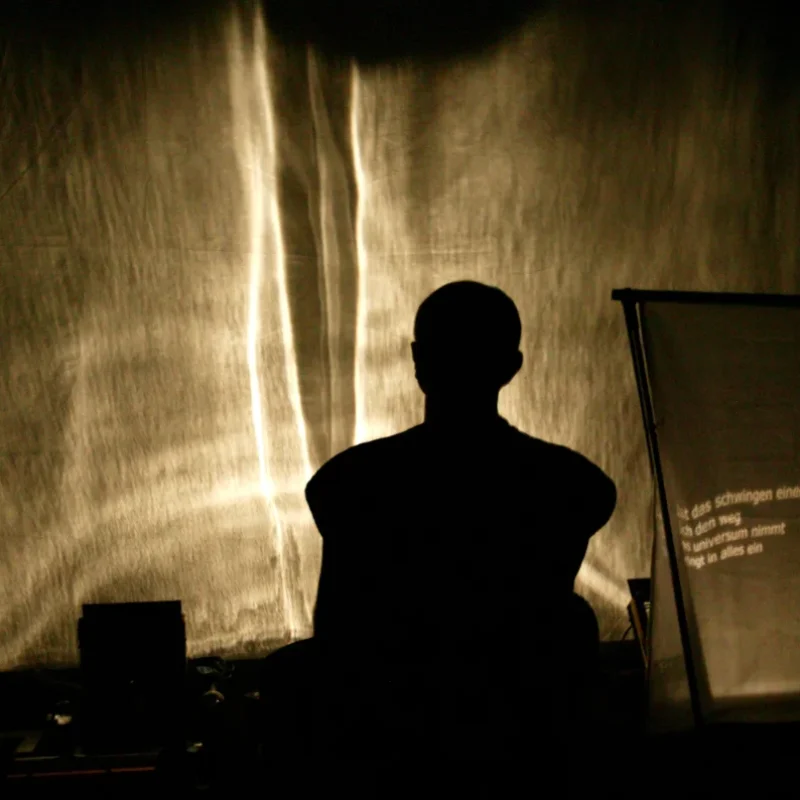 Silhouette eines Performers vor leuchtendem Leinwandhintergrund mit projiziertem Text – Schattentheater Theater der Schatten Bamberg