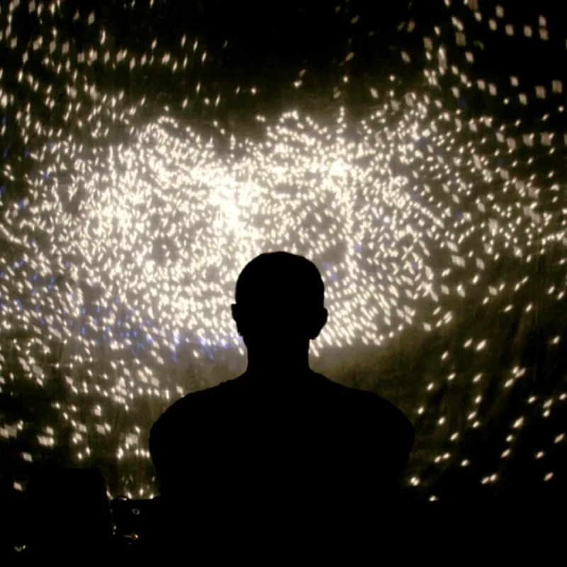 Silhouette eines Performers vor funkelndem Lichtmuster auf Leinwand – Schattentheater-Performance „17 Sätze über das Licht"