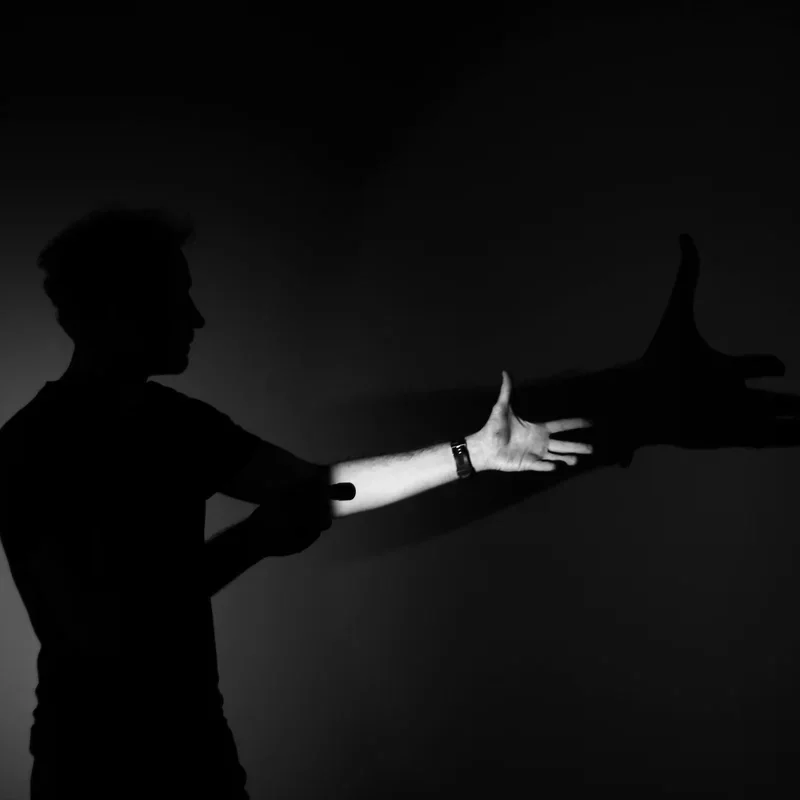 Teilnehmer formt mit ausgestrecktem Arm einen Schattenvogel an der Wand – Schattentheater-Workshop Theater der Schatten